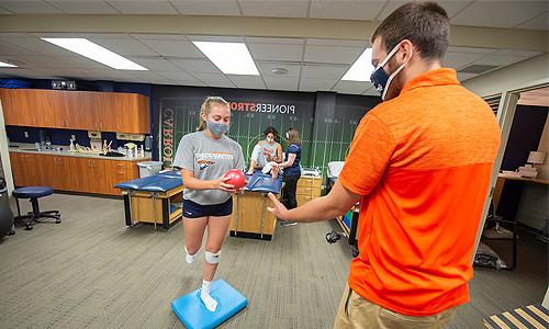 Image of a staff coaching a student in the Athletic Training Suite.